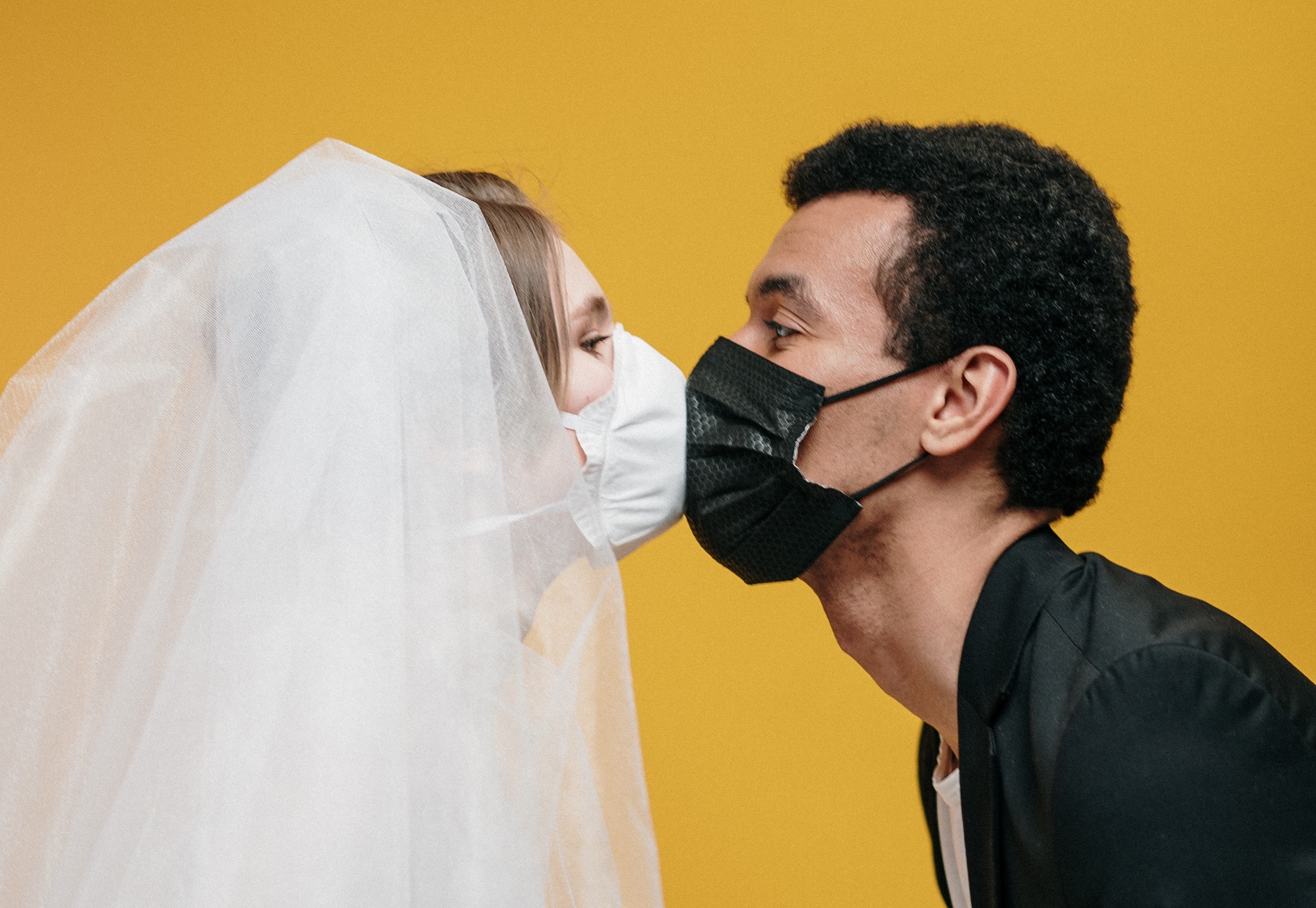 Dos personas con mascarillas faciales besándose